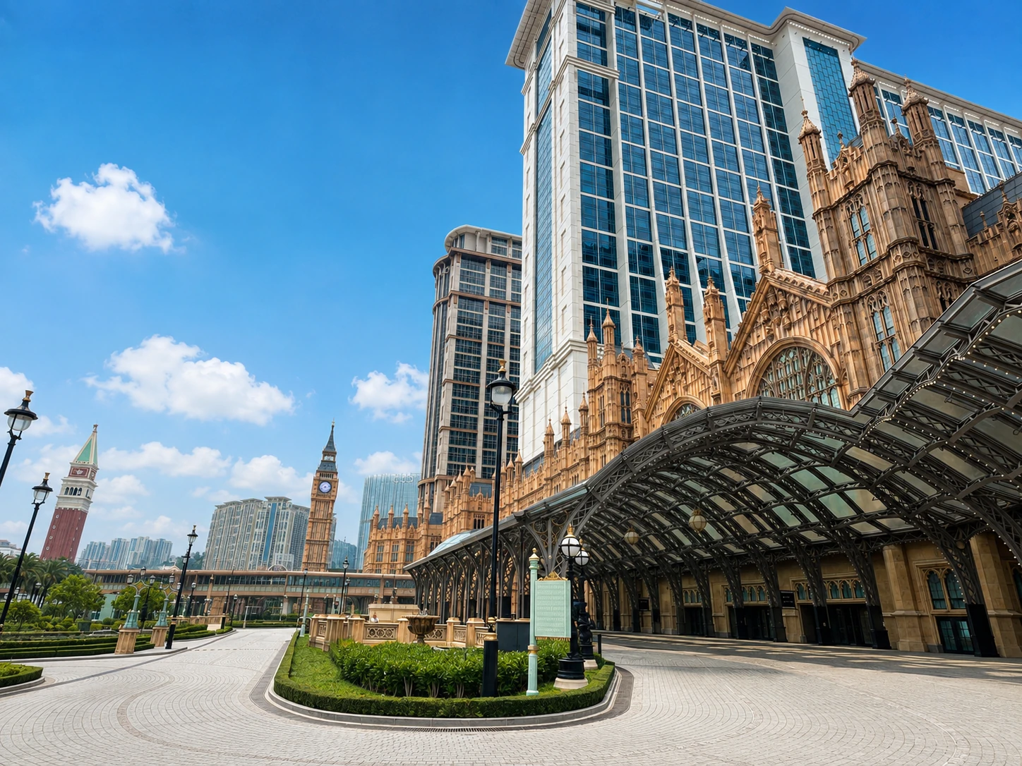 The facades of luxury hotels in Macau, with a glass-canopied entrance driveway under a clear blue sky